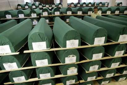 A worker walks between coffins of victims of the 1995 Srebrenica massacre prepared for burial in a morgue in Visoko July 7, 2004. The mass burial of about 300 victims of the 1995 massacre of up to 8,000 Muslim men and boys by Bosnian Serb forces is scheduled for July 11 at a joint cemetery near Srebrenica.     REUTERS/Danilo Krstanovic